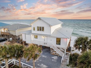 A two-story beachfront property with a covered patio, a staircase leading to the upper level, and a view of the ocean. - A Grand View – Stunning Gulf Views & Direct Beach Access (Santa Rosa Beach)