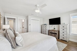 A bedroom with a large bed, a ceiling fan, a TV mounted on the wall, and a dresser with drawers. - A Grand View – Stunning Gulf Views & Direct Beach Access (Santa Rosa Beach)