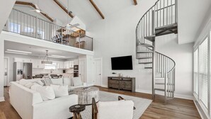 Ein geräumiges Wohnzimmer mit einem weißen Sofa, einem Couchtisch und einer Treppe.