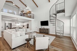 Ein geräumiges Wohnzimmer mit einem weißen Sofa, einem Couchtisch und einer Treppe.