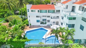 A modern building with a swimming pool surrounded by lush greenery. - CONDO OLA ALEGRE (Manzanillo)