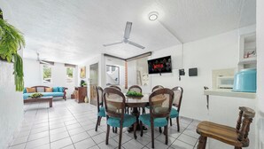 A dining area with a round table, chairs, and a television mounted on the wall. - CONDO OLA ALEGRE (Manzanillo)