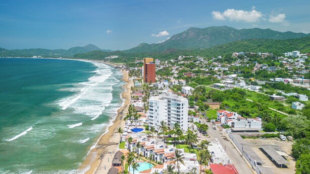 A coastal town with a beach, a tall building, and lush greenery. - CONDO OLA ALEGRE (Manzanillo)