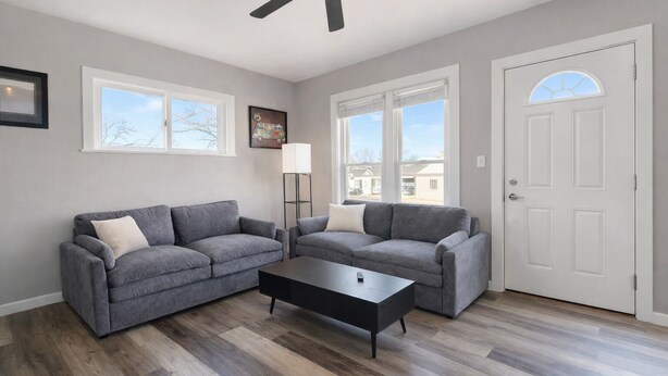 A living room with two grey sofas, a black coffee table, and a white door.