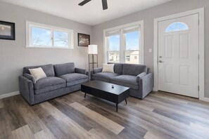 A living room with two grey sofas, a black coffee table, and a white door. - Oshkosh's #1 Home Away From Home (Oshkosh)