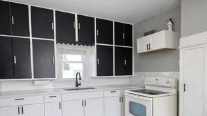 A kitchen with white cabinets, a stove, and a microwave.