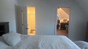 A bedroom with a bed, a fluffy pillow, and a door leading to a bathroom and a kitchen area. - Newly renovated 1 Bedroom apartment in Alton, Ontario (Alton)