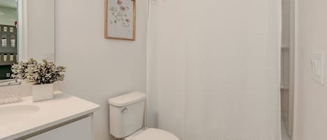 A bathroom with a toilet, sink, and shower curtain.