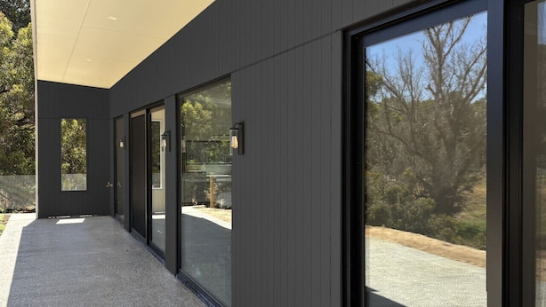 A modern building with a covered walkway, large glass doors, and a view of the surrounding landscape. - Modern Luxe Bush Retreat | 3BR Near Trails (Nannup)
