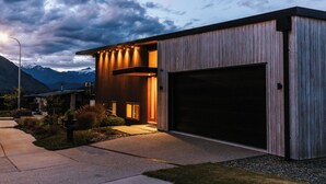 Ett modernt hus med ett stort garage, en väl upplyst entré och en vacker bergsutsikt.