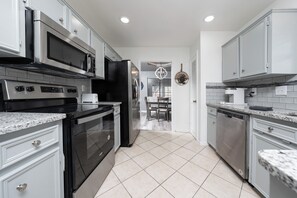 A modern kitchen with stainless steel appliances, white cabinetry, and a tiled floor. - Modern Chic 3/2 Close to Fort Hood, Huge Master Bedroom, Great Neighborhood (Killeen)