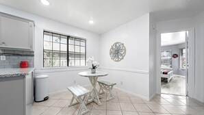 Una cocina con ventana, una mesa redonda y un cubo de basura.
