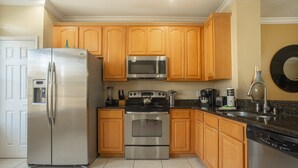 Una cucina con mobili in legno, elettrodomestici in acciaio inossidabile e pavimento piastrellato.