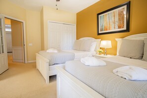 A hotel room with two beds, a white wardrobe, a framed picture on the wall, and a door leading to another room. - Spacious 3BR Townhouse in Vista Cay – Sleeps 8 Near Disney (Orlando)