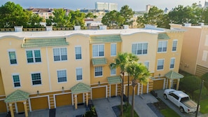 A multi-story building with a uniform facade, multiple windows, and a parking area with a white vehicle. - Spacious 3BR Townhouse in Vista Cay – Sleeps 8 Near Disney (Orlando)
