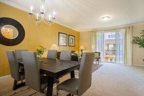 A dining area with a table, chairs, a chandelier, and a large mirror on the wall. - Spacious 3BR Townhouse in Vista Cay – Sleeps 8 Near Disney (Orlando)