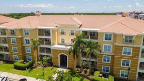 A multi-story hotel with a yellow facade, red-tiled roof, and balconies. - Spacious 3BR/2BA Apartment at Vista Cay, Minutes from Disney & Universal (Orlando)