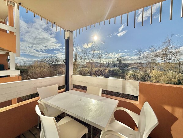 An outdoor patio with a white table and chairs, a view of a desert landscape, and a clear sky. - CAP D'AGDE - Plage Richelieu / Réf 0260 (CAP D'AGDE)
