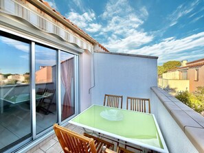 Ein Balkon mit Glastür, einem Tisch und zwei Stühlen.