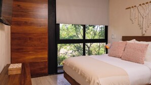 Een slaapkamer met een groot raam, een bed met wit beddengoed en een houten wand.