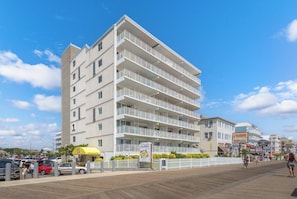 A multi-story hotel with balconies, a boardwalk in front, and a beach view. - On Boardwalk - Oceanfront 2 Bed/2 Bath (Ocean City)