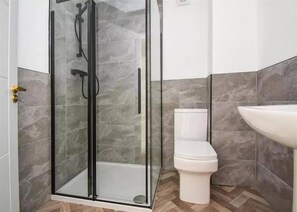A modern bathroom with a glass-enclosed shower, a toilet, and a sink. - Glams Beautiful Luxury Home (Wolverhampton)