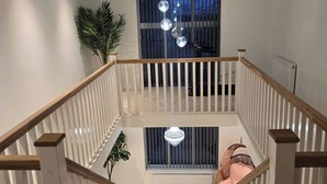 A modern staircase with white railings and wooden handrails, leading to a balcony with a view of the outside. - Glams Beautiful Luxury Home (Wolverhampton)