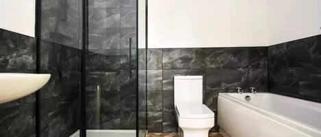 A modern bathroom with a glass shower enclosure, a toilet, and a bathtub.