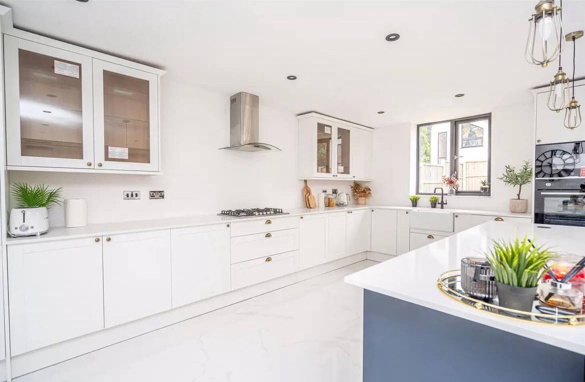 Een moderne keuken met witte kastjes, een gasfornuis en een groot raam voor natuurlijk licht.