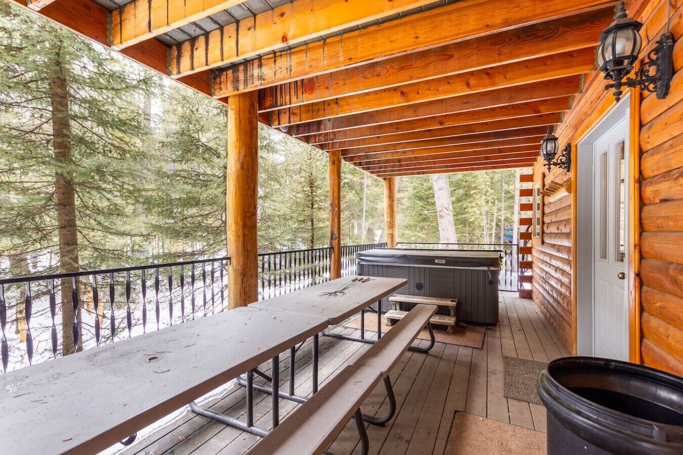 Un espacio al aire libre techado con una mesa de picnic, un jacuzzi y una terraza de madera.