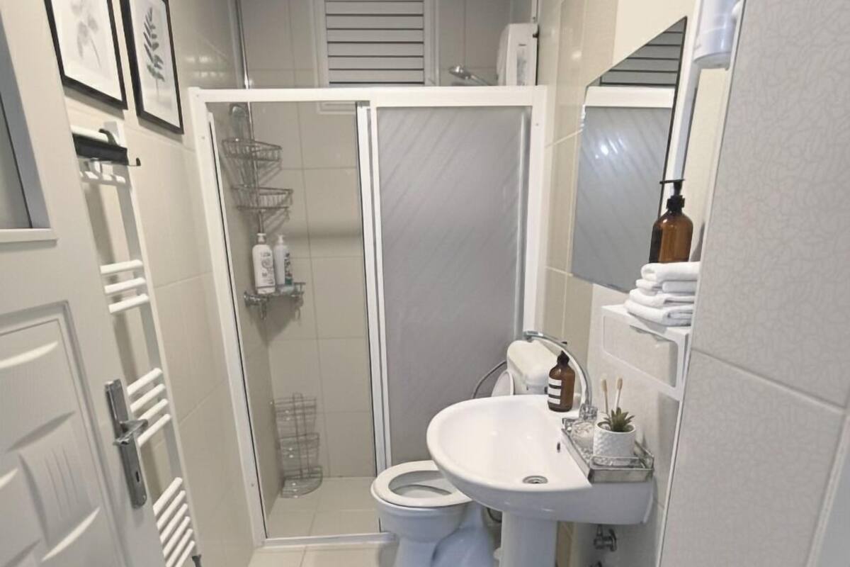 A compact bathroom with a shower, toilet, and sink.