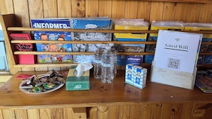 A wooden reception desk with brochures, a guest wifi sign, bottled water, and a tissue box. - Bunkhouse Motel Cooma (Cooma)