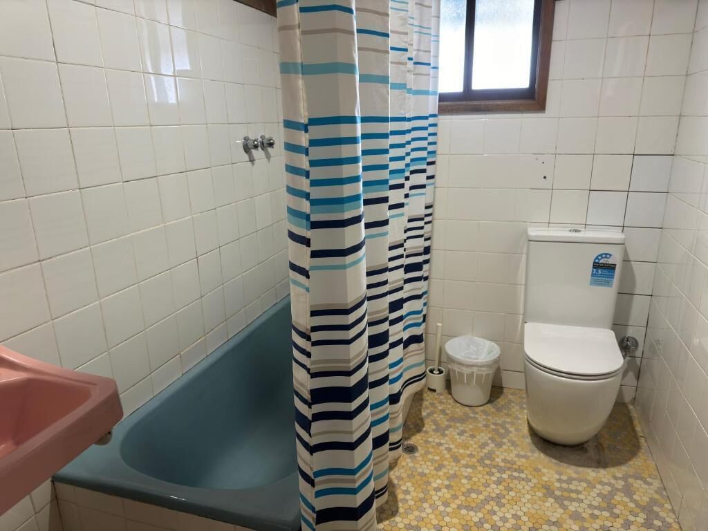 Un baño con bañera, inodoro y cortina de ducha.