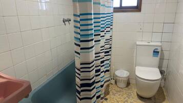 Un baño con bañera, inodoro y cortina de ducha.