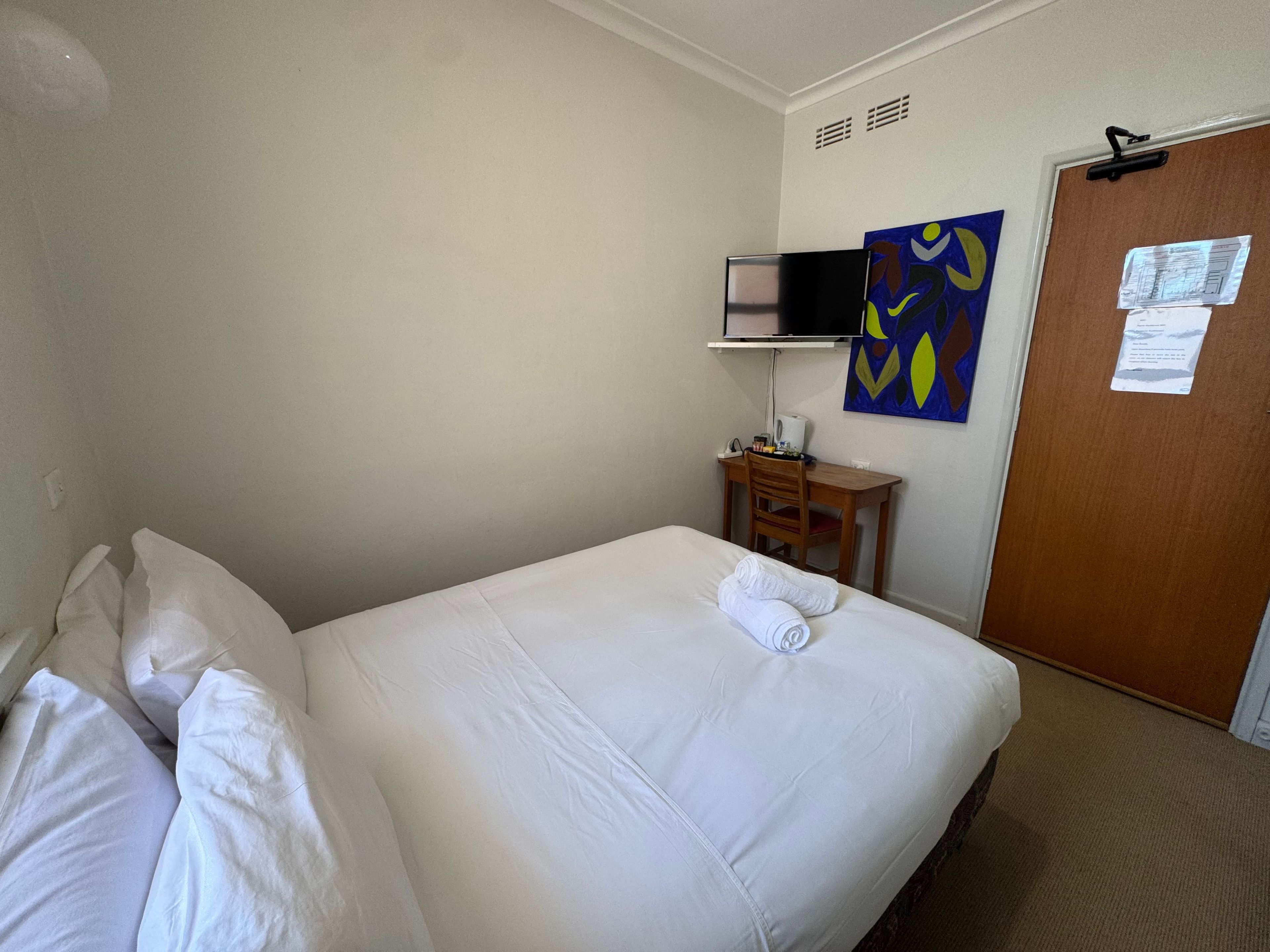 Une chambre d’hôtel avec un lit, une télévision, un bureau et une porte.