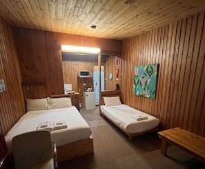 A wooden cabin room with two beds, a small desk, a microwave, and a painting on the wall. - Bunkhouse Motel Cooma (Cooma)