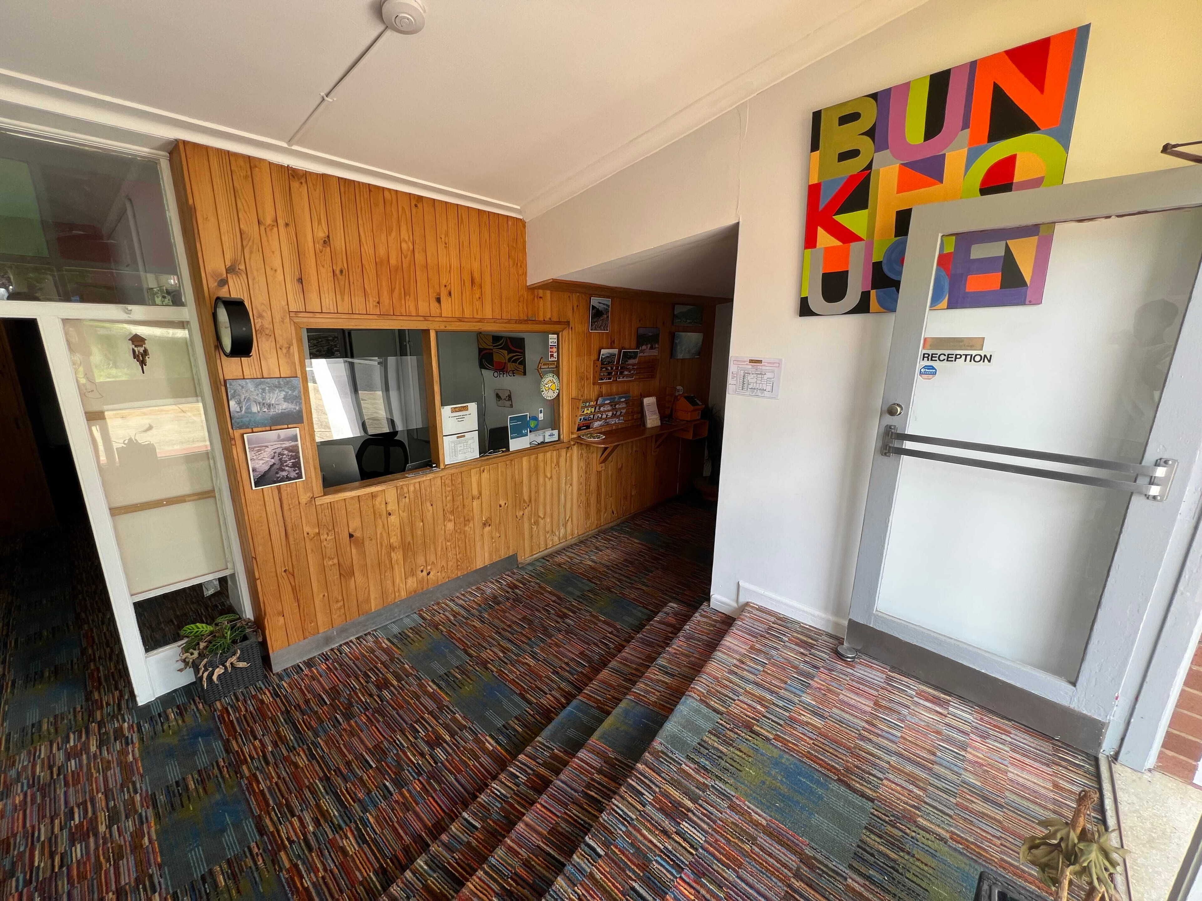 A reception area with a wooden panel wall, a reception desk, and a colorful wall art piece.