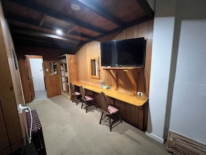 A room with a wooden ceiling, a TV mounted on the wall, a wooden desk, and four chairs. - Bunkhouse Motel Cooma (Cooma)