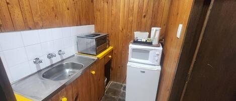 Una cocina compacta con un fregadero, un microondas y un tostador.