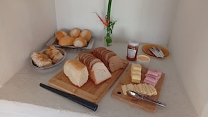 Une variété d’aliments, notamment du pain, du fromage et du jambon, disposés sur une planche à découper en bois.