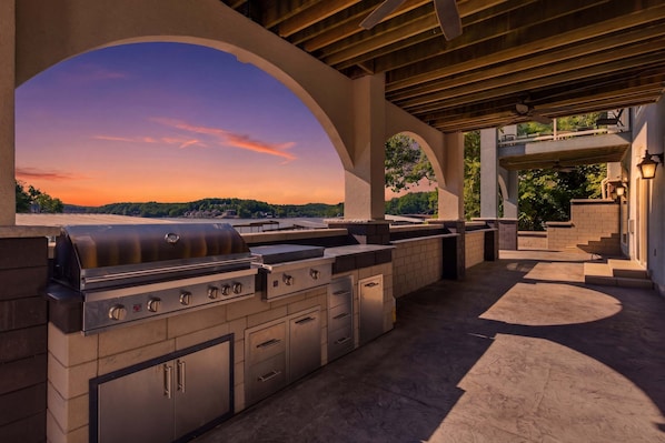 Une cuisine extérieure équipée d’un barbecue, de placards intégrés et offrant une vue sur le paysage.