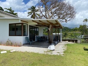 A modern house with a covered patio, a lawn, and a view of the surrounding landscape.