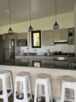 A modern kitchen with a central island, stainless steel appliances, and pendant lighting.