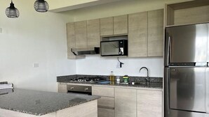 A modern kitchen with a central island, stainless steel appliances, and light wood cabinetry. - Lovely Caribbean Apartment with AC + Wifi + BBQ + Beach + Kitchen + Parking (Puerto Lindo)