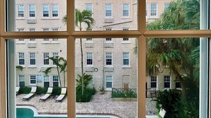A building with multiple windows and balconies, a pool area with sun loungers, and some greenery. - The Green Room - Serene Poolview Studio with Parking Spot and 24x7 Front Desk (Palm Beach)