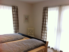 A bedroom with a bed, two pillows, a small white chair, and a framed picture on the wall. - Strandläufer EG by Interhome (Breege)