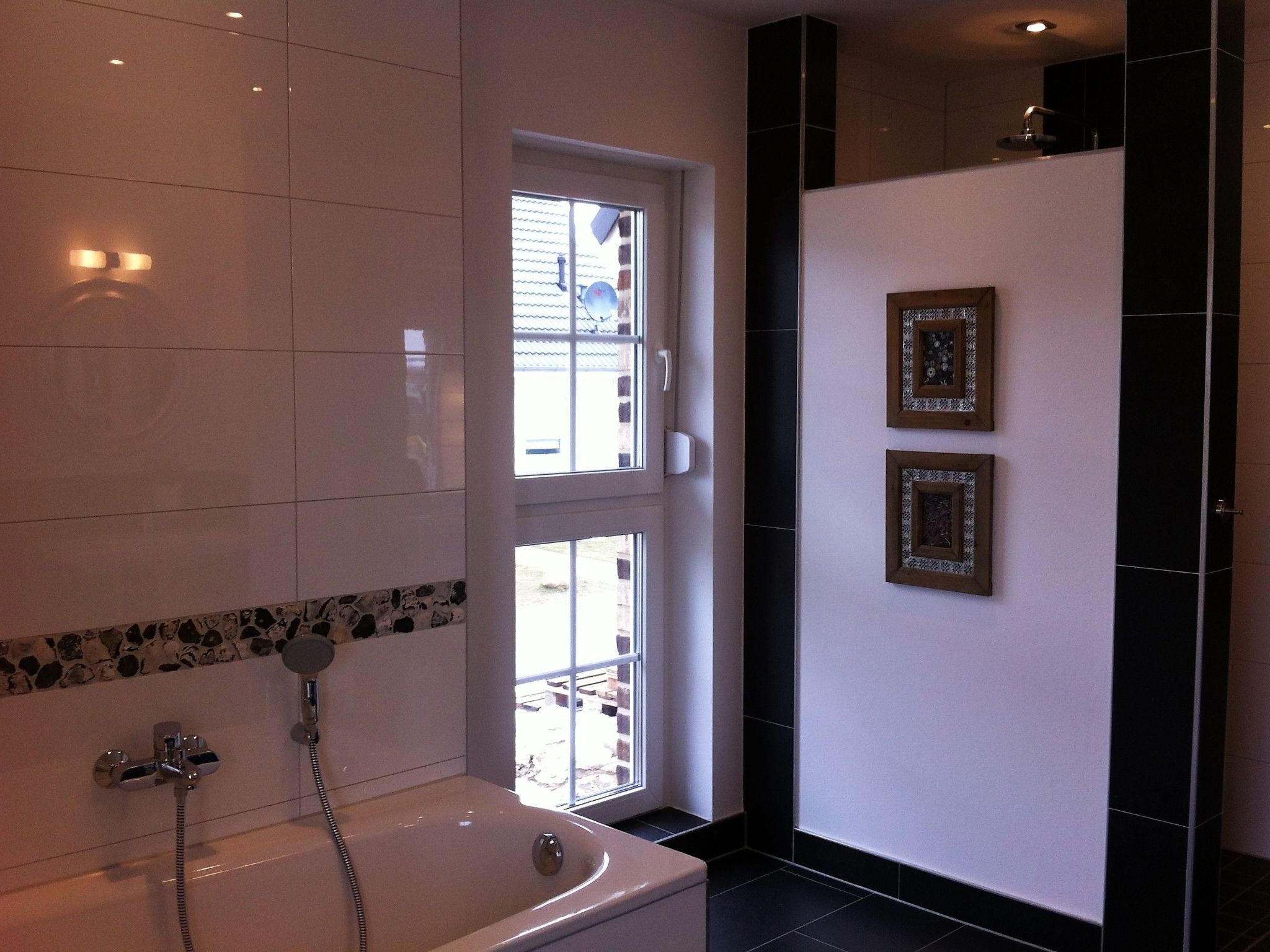 Un baño moderno con una bañera, una ventana y dos cuadros enmarcados en la pared.