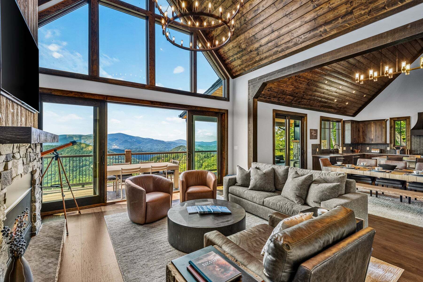 Amplia sala de estar con un ventanal que ofrece vistas a un paisaje montañoso, un rincón de descanso acogedor y una cocina moderna.