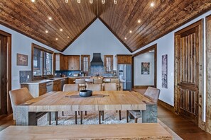 A spacious kitchen with wooden cabinets, a central island, and a large dining table. - Skyrise at Eagles Nest - Layered mountain views, luxury home (Banner Elk)