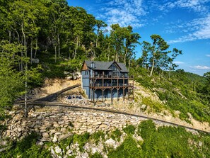 A house with a balcony, surrounded by trees and a stone pathway. - Skyrise at Eagles Nest - Layered mountain views, luxury home (Banner Elk)